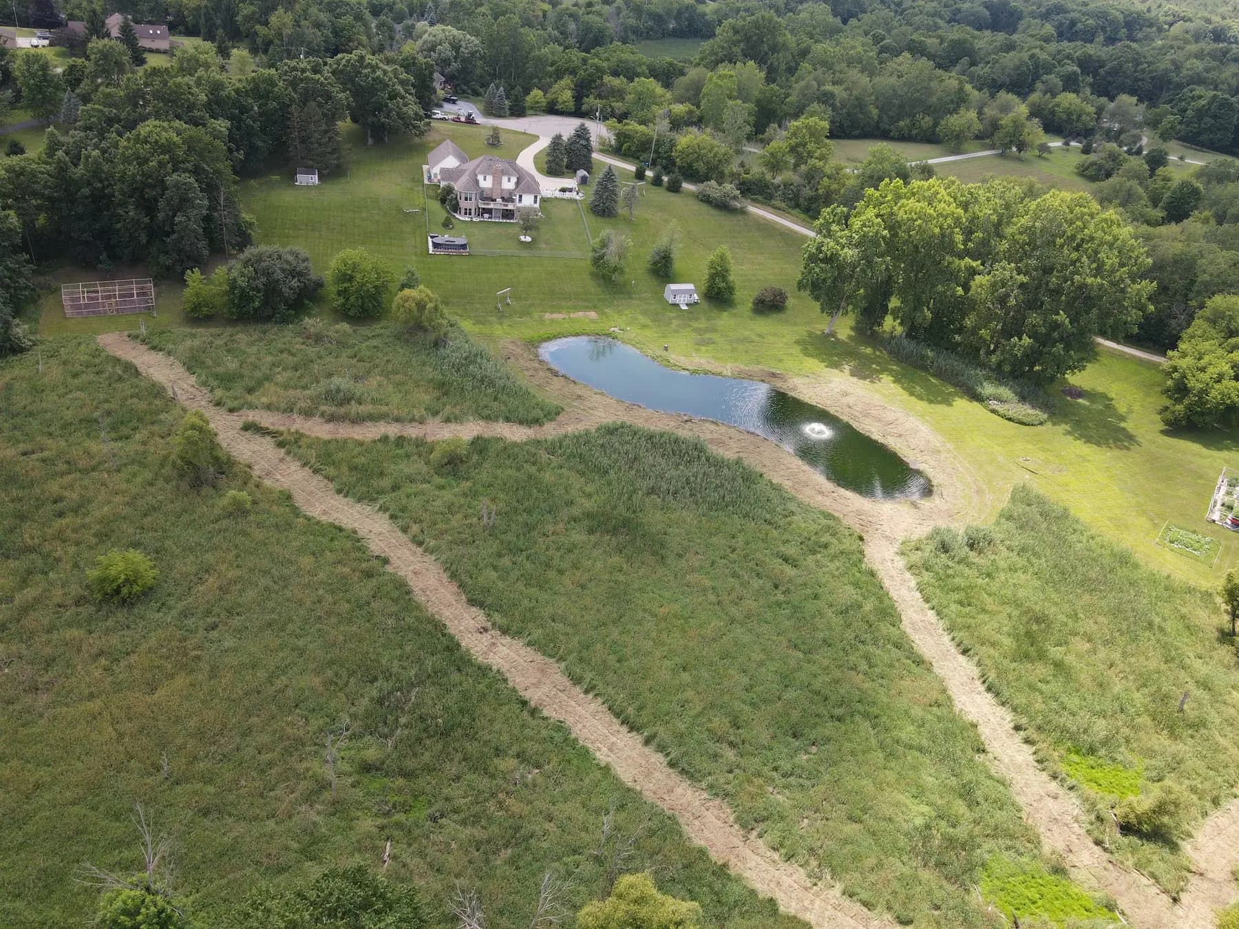 Aerial view of mulched walking paths around a pond on wooded acreage
